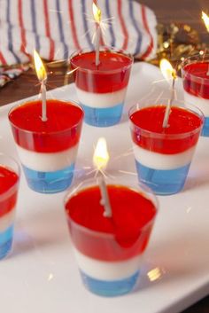 red, white and blue cupcakes with candles in them on a platter