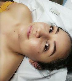 a woman laying on top of a bed next to a white sheet and pillow with her eyes closed