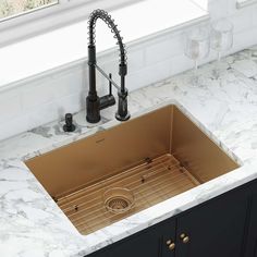 a kitchen sink under a faucet with marble counter tops and black cabinetry