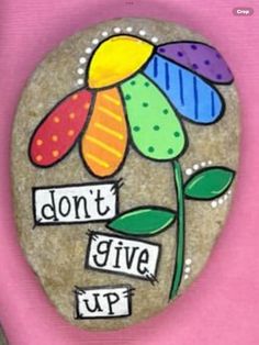 a painted rock with the words don't give up and a flower on it