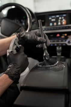 a person cleaning the inside of a car's dashboard with a scrubber and glove