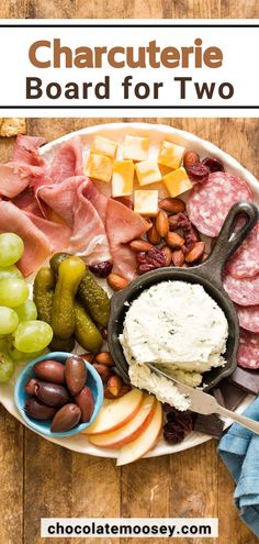 a platter filled with meats, cheese and fruit on top of a wooden table