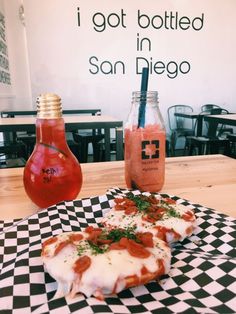 two slices of pizza sitting on top of a checkered table cloth next to jars