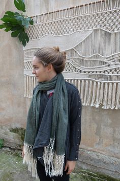 a woman standing in front of a wall with a green scarf on it's neck