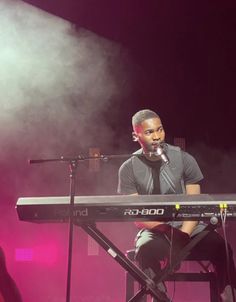 a man sitting at a keyboard in front of a microphone on top of a stage