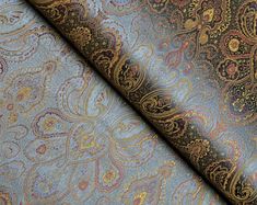 a close up view of a blue and gold paisley pattern on a piece of fabric