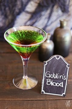 a green and red drink in a glass next to a sign that says gosling's blood