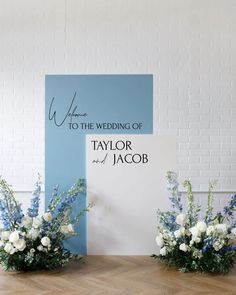 two vases filled with flowers sitting on top of a wooden floor next to a sign