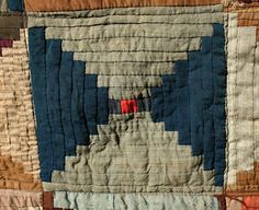 an old quilt with blue and brown squares on it's sides, including one red square