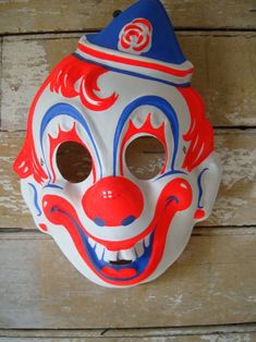 a red, white and blue clown mask hanging on a wall