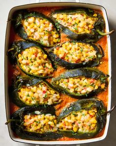 an overhead view of stuffed peppers in a casserole dish with corn on the cob