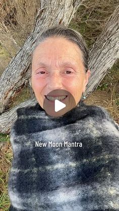 an old woman is smiling and wearing a black and white blanket with the words new moon mantra on it