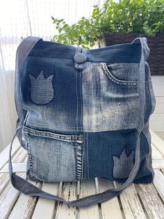 a bag made out of old jeans on top of a wooden table next to a potted plant