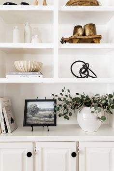 a white shelf filled with books and vases on top of it's shelves