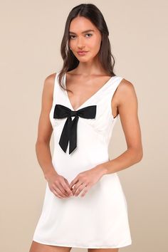 However you decide to style the Motel Faradiba Ivory Satin Sleeveless Bow Mini Dress, we know it'll be on trend! Sleek woven satin shapes this sleeveless dress that features a lightly gathered bodice, a flirty V-neck (and back), and wide tank straps. A high, empire-style waist tops a figure-skimming sheath silhouette that falls to a flirty mini hem. A darling black bow accents the front of this dress for the perfect coquette finish. Hidden side zipper. Fit: This garment fits true to size. Length Satin Sleeveless Dress With Fitted Bodice, Sleeveless Evening Dress With Bow, Elegant Sleeveless Dress With Bow For Party, White Sleeveless Evening Dress, Elegant Sleeveless Dress With Bow, White Sleeveless Mini Dress For Evening, Satin Sleeveless Party Dress, Elegant Fitted Sleeveless Dress With Bow, Formal Sleeveless Dress With Satin Bow