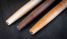 three wooden baseball bats sitting next to each other on a black surface with an orange ball in the background