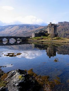 an old castle is reflected in the still water