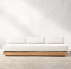 a white couch sitting on top of a wooden frame in front of a gray wall