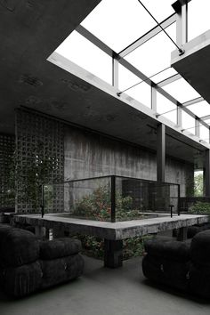 an empty room with couches, tables and plants on the floor in front of it