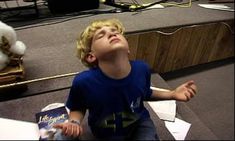 a young boy sitting on the floor with his eyes closed