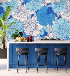 three stools in front of a counter with blue flowers on the wall behind it