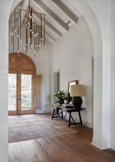 an image of a living room with wood flooring and chandelier hanging from the ceiling