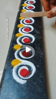 someone is using a wooden spoon to paint the sushi on the surface with white, yellow and red colors