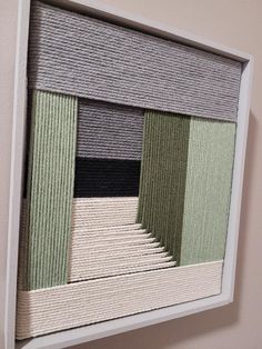 an art piece hanging on the wall with different shades of green and grey in it