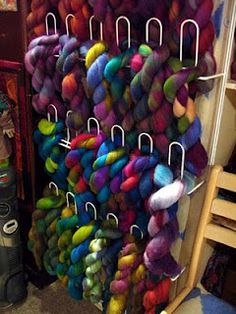 there are many skeins of yarn hanging on the rack in this room,