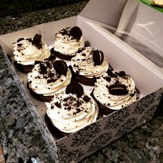 a box filled with lots of cupcakes on top of a marble countertop