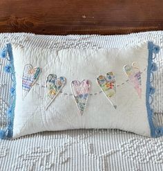 an embroidered pillow with hearts hanging from it