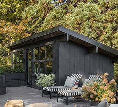 an outdoor living area with black and white furniture, potted plants, and trees in the background