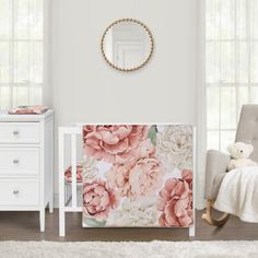 a baby's room with white furniture and pink flowers on the wall, along with a teddy bear