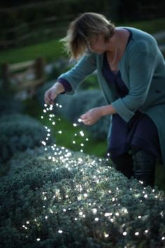 a woman kneeling down in the grass with her hand on top of some water droplets