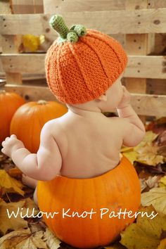 a baby sitting on top of a pumpkin wearing a knitted hat and diaper