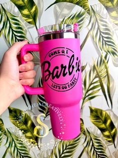 someone is holding a pink coffee mug with the name barbie's in black on it