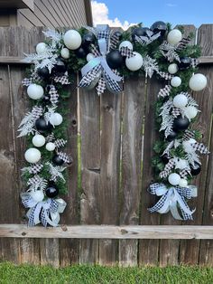 a wreath with black and white ornaments hanging on a fence