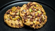 two cookies with nuts and pistachios on a black plate