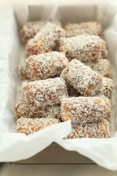 a box filled with lots of powdered sugar covered treats on top of white paper