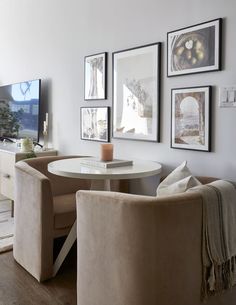 a living room filled with furniture and framed pictures on the wall above a round table