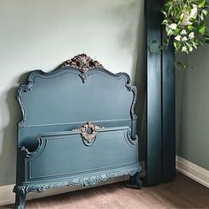 a blue bed sitting in the corner of a room next to a tall green plant