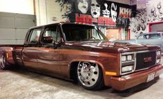 a brown truck parked in a garage next to another car and some graffiti on the wall