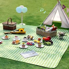 an outdoor picnic with food and drinks on the grass in front of a teepee tent