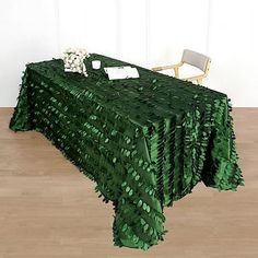 a table covered in green leaves with a chair next to it on a hard wood floor