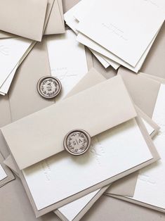 a bunch of white envelopes with some silver buttons on them