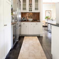 a kitchen with white cabinets and an area rug in front of the counter top oven