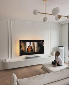 a child sitting on a couch in front of a flat screen tv that is mounted to the wall