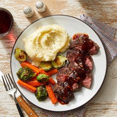 a white plate topped with meat, vegetables and mashed potatoes