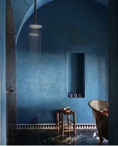 a bathroom with blue walls and an old bathtub in the corner, next to a wooden chair