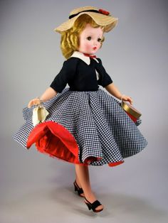 a doll dressed in a dress and hat with a purse on her hip is standing